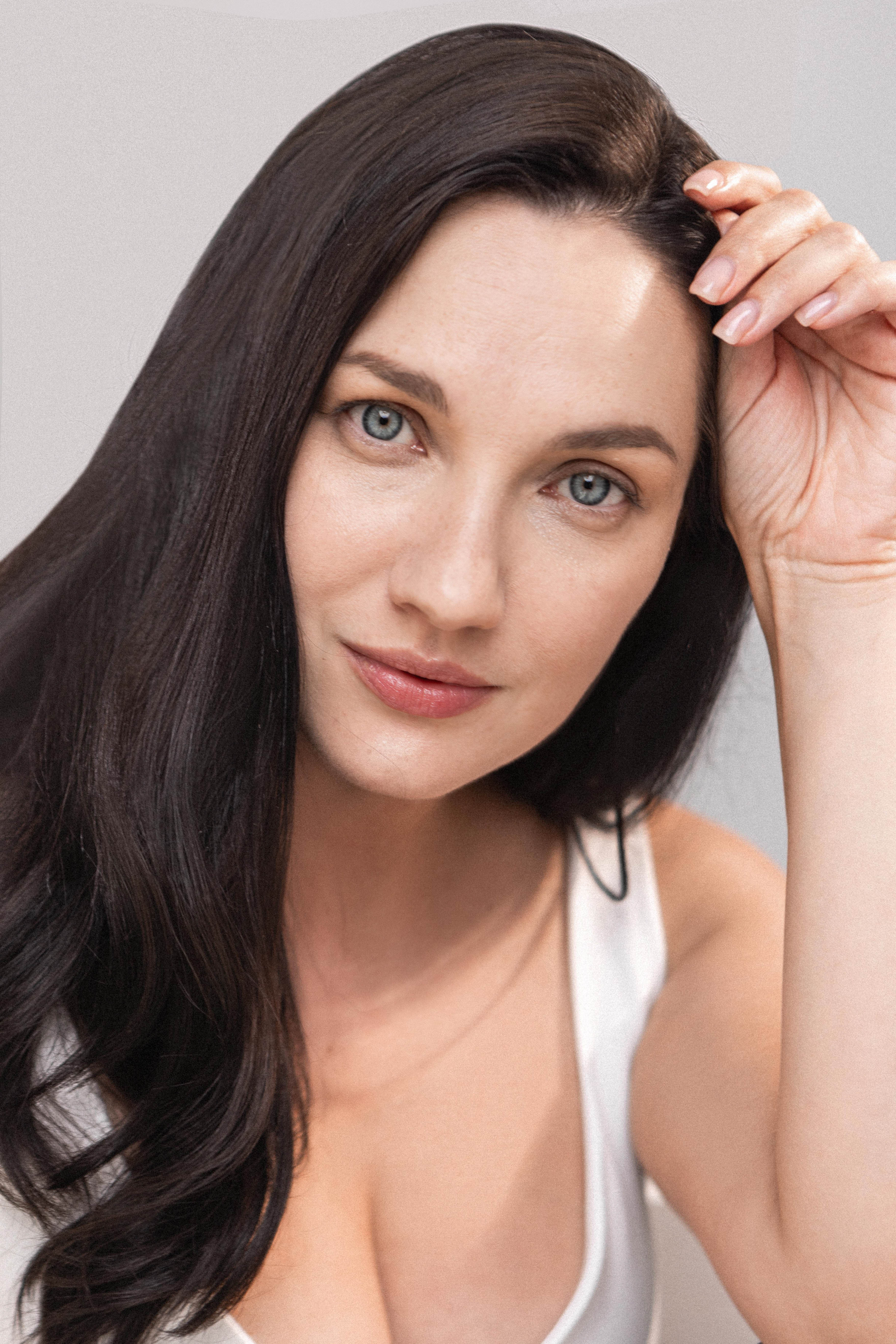 Woman with long dark hair against a plain background. Brand paradigm 99.