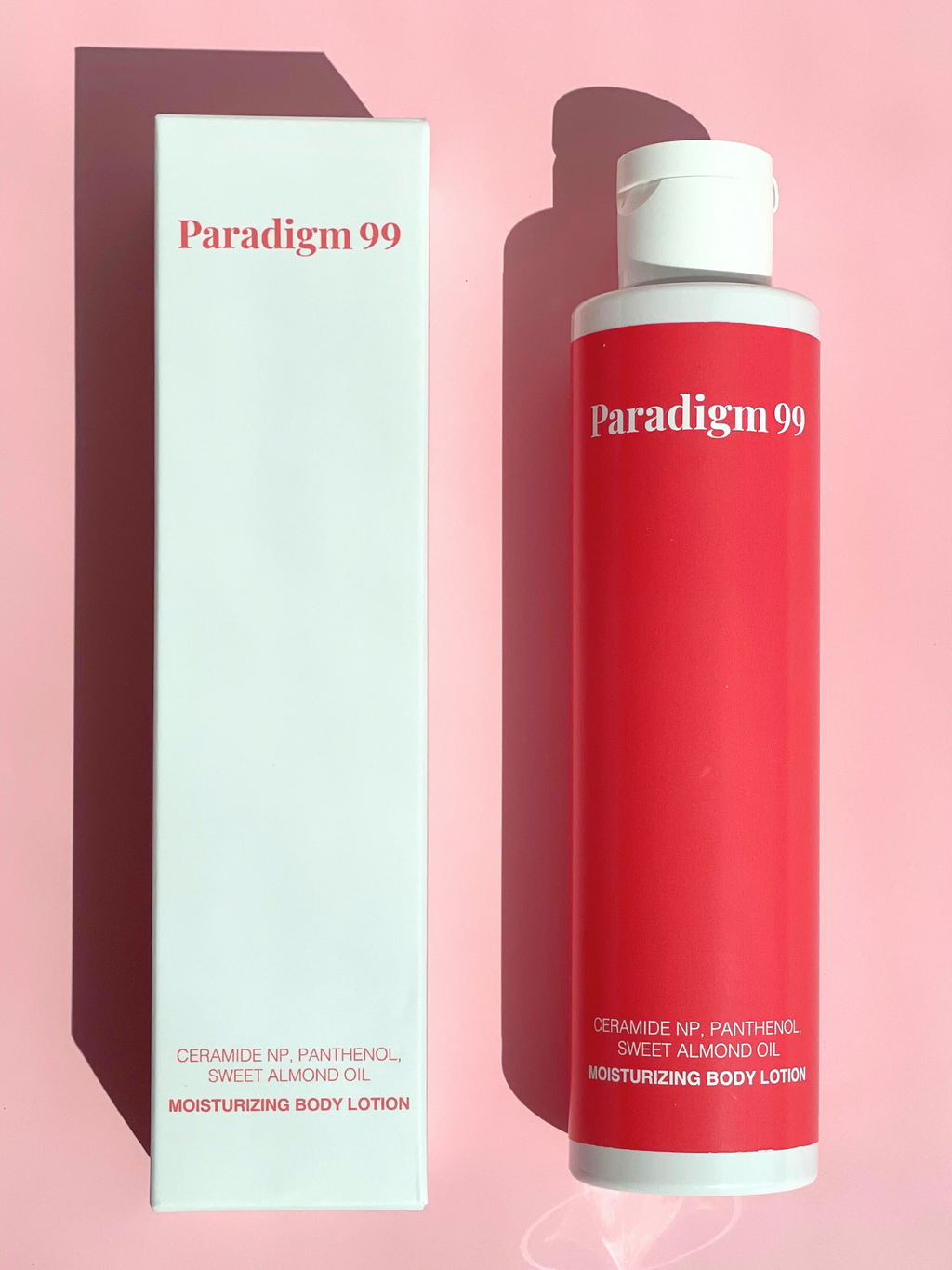 Paradigm 99 moisturizing body lotion with beauty box packaging on a pink background.
