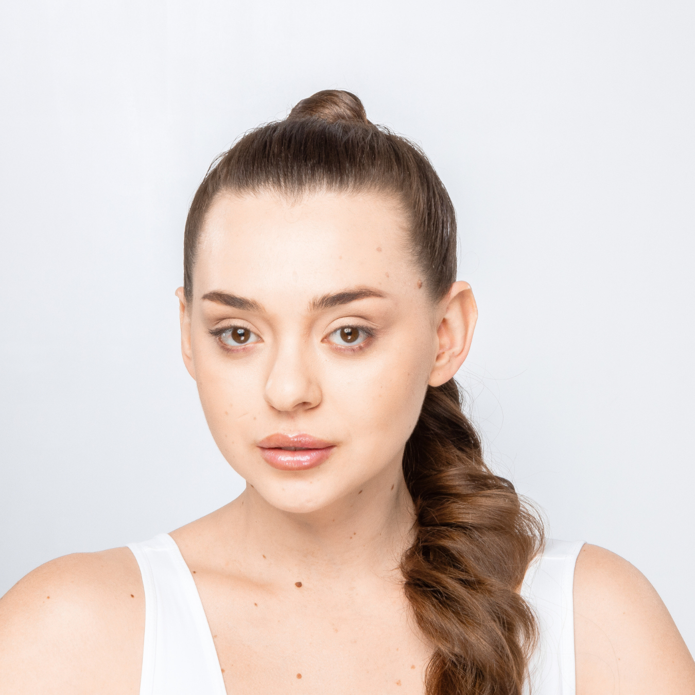 Woman with a ponytail against a plain background after Peptide Face Treatment, brand Paradigm99.